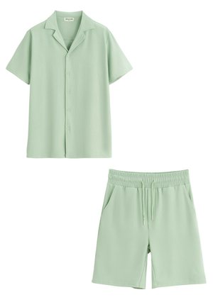 Chemise vert clair à manches courtes avec col et boutons, et shorts assortis à taille élastique avec cordon. Les deux ont une texture côtelée.