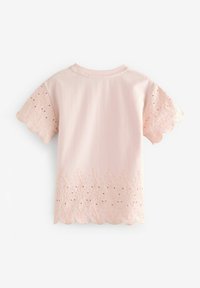 Camisa de manga corta en rosa claro con detalles de encaje con borde en forma de ondas en el dobladillo y las mangas, bordados y pequeños cortes con ojales.