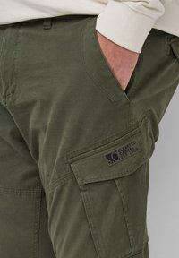 Olijfgroene cargobroek gemaakt van een katoenmengsel, met een zijzak voorzien van een logopatch en een gladde textuur.