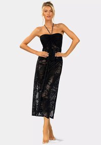 Czarna koronkowa sukienka maxi bez ramiączek z marszczonym przodem, o przezroczystej fakturze i kwiatowych wzorach, zwężająca się w talii.
