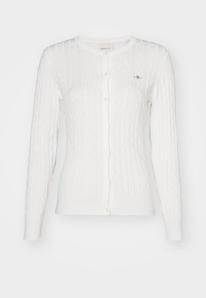 Witte kabelgebreide cardigan met lange mouwen, ronde hals en knoopsluiting. Heeft subtiele ribbels langs de randen en een klein logo op de borst.