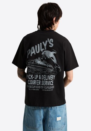 Persoon die een zwart T-shirt draagt met een afbeelding van een dolfijn die een persoon uit een boot redt en tekst over een ophaal- en bezorgkoeriersdienst.