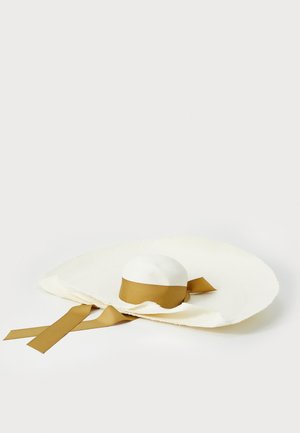 Breiter Hut aus gewobenem Stroh in Creme, mit einer abgerundeten Krone und einem braunen Band, das um die Basis gebunden ist, mit flatternden Bänder-Akzenten.