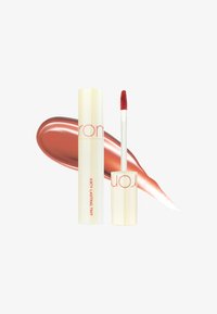 Teinte à lèvres liquide dans un tube crème avec du texte rouge. Accompagnée d'un échantillon de produit avec des nuances de rouge chaud. Applicateur visible.