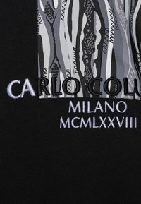 Il tessuto nero presenta un quadrato grigio a motivi con linee astratte. Il testo in bianco e nero recita "CARLO COLUMBIA," "MILANO," e "MCMLXXVIII."