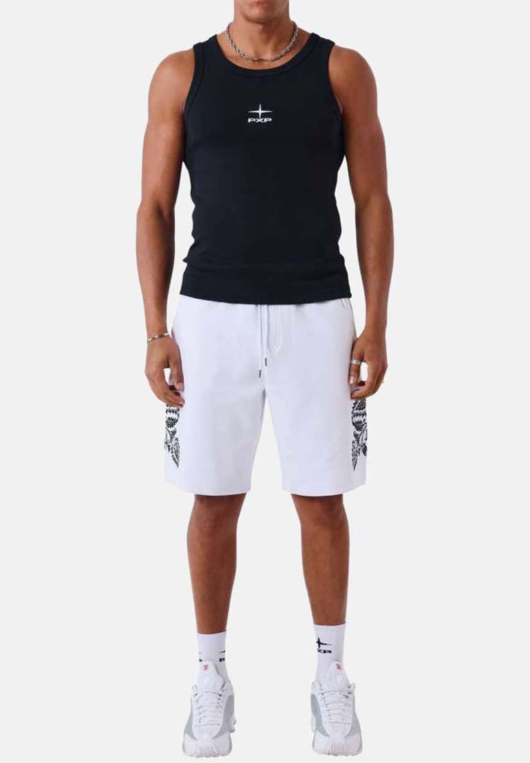 Homme portant un débardeur noir sans manches, un short blanc avec des motifs noirs sur les côtés, des chaussettes blanches et des baskets blanches, debout devant un fond uni.