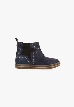 Stivaletti ankle in suede blu navy con un design a stella in elastico nero, dettagli borchiati e suola testurizzata, dotati di una linguetta per facilitare l'indossamento.