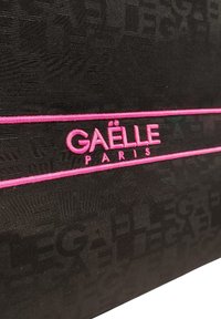Borsa in tessuto nero con motivi testurizzati, accentuata da un logo ricamato fucsia brillante e una striscia orizzontale rosa.