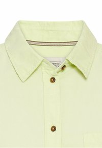 Lys grøn corduroy skjorte med spids krave, der har brune knapper og subtile stribede detaljer nær kraven. Enkelt brystlomme.