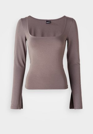 Pikkade varrukatega topp pehmest pruuni kangast. Omab ruudukujulist kaelust ja külgfreesidega hemmi. Sile tekstuur ja sobiv disain.