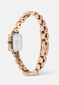 Bracelet de montre en métal rose gold avec un fond en acier inoxydable carré et une couronne latérale, présenté sur un fond blanc.