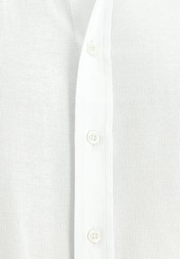 Camicetta bianca a maglia con una fila di bottoni sul davanti, texture liscia e design aderente.