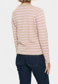 Ljusbeige långärmad tröja med rosa ränder, med rund halsringning och ribbade ärmslut, kombinerad med mörkblå jeans.