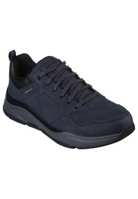 Scarpa da ginnastica blu navy con tomaia in suede, dettagli in rete, suola in gomma spessa e punta rotonda. Design con lacci e collo imbottito.