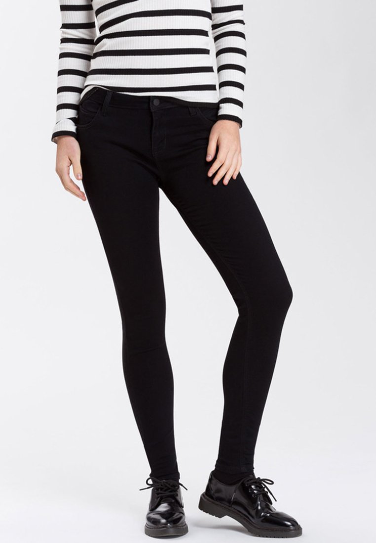 Czarne wąskie dżinsy z elastycznej bawełnianej mieszanki. Posiadają klasyczny fason z pięcioma kieszeniami i dopasowany krój. Noszone z paskowanym topem i czarnymi butami.