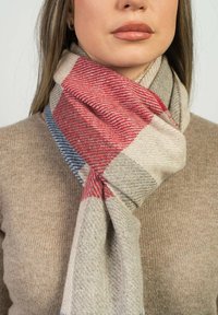 Vævet uldhalstørklæde med et houndstooth-mønster i beige, rød og blå, blødt tekstur og lagdelt drapering omkring halsen.