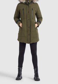 Olivgrön vadderad parka med huva kantad av päls, två dragkedjefickor på bröstet och sidfickor. Svarta accenter och ribbade cuffar.