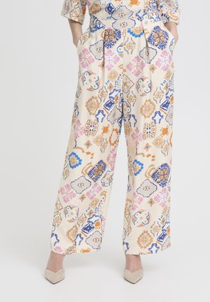 Broek met hoge taille en wijde pijpen met kleurrijke abstracte bloem- en geometrische patronen in blauw, roze, oranje en beige op een crèmekleurige achtergrond.