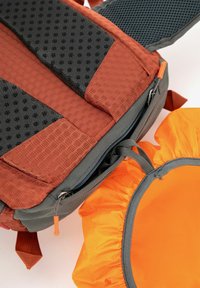 Backpack with honeycomb-patterned red material and gray accents, featuring a zipper closure and bright orange drawstring pouch.