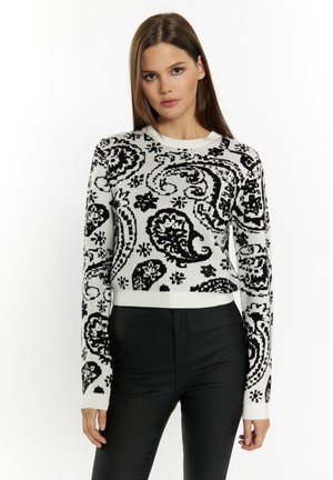 Maglione a righe bianco e nero con motivo paisley, colletto rotondo, maniche lunghe e polsini a costine, abbinato a pantaloni neri a vita alta.