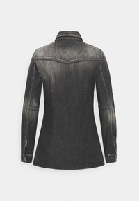 Zwarte spijkerjasje met lange mouwen, een getailleerde pasvorm, een puntige kraag en subtiele vervagingen in de stof. Voorzien van sierstiksels en knoopmanchetten.