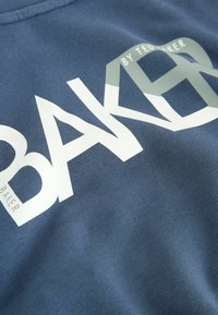 Felpa blu navy con grande scritta grafica bianca "BAKER" e "by TED BAKER", realizzata in un tessuto morbido e dalla texture liscia.