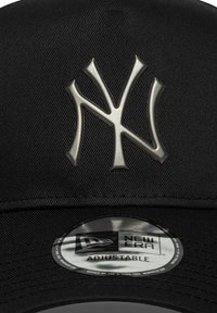 Μαύρο καπέλο με ρυθμιζόμενο μέγεθος και υφασμάτινη υφή, με μεταλλικό γκρι λογότυπο των New York Yankees στο μπροστινό μέρος και κυκλικό ταμπελάκι 'New Era' από κάτω.