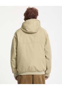 Giacca beige con cappuccio, dalla texture liscia, con polsini ed orlo elasticizzati. Presenta un design semplice e un dettaglio di cucitura posteriore.