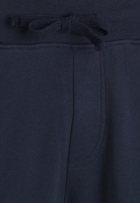 Marinblå mjukisbyxor med elastisk midja och knytband samt synliga sömmar på sidofickorna i mjukt tyg.