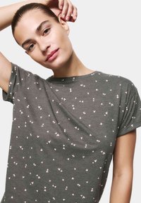 Graues Kurzarm-T-Shirt aus weichem Stoff, das ein verstreutes pinkes Herzmuster auf der Oberfläche und einen lässigen Schnitt aufweist.