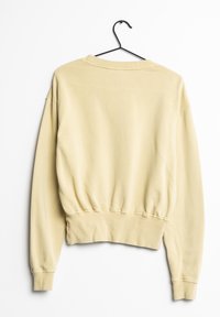Sudadera de color amarillo claro, de manga larga, con puños y dobladillo acanalados. Presenta un escote de cuello redondo y un corte relajado. Tejido de textura cómoda.
