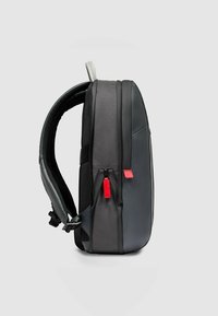 Sac à dos noir au design élégant, combinant des surfaces lisses et texturées, avec des tirettes de fermeture éclair rouges et des bretelles rembourrées.