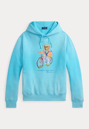 Sweat à capuche bleu clair avec un motif d'ours à vélo. Il est doté d'une capuche ajustable par cordon de serrage et de poignets et ourlet côtelés. Confectionné en tissu doux.