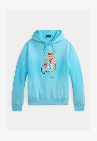 Sweat à capuche bleu clair avec un motif d'ours à vélo. Il est doté d'une capuche ajustable par cordon de serrage et de poignets et ourlet côtelés. Confectionné en tissu doux.