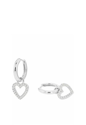 Silver hoop earrings with dangling open heart-shaped charms encrusted with small clear gemstones on a white background.
