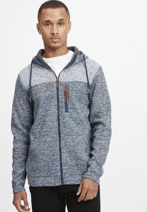 Felpa con zip di colore blu scuro e grigio mélange, con una texture liscia, tasca frontale e cordini regolabili nel cappuccio.