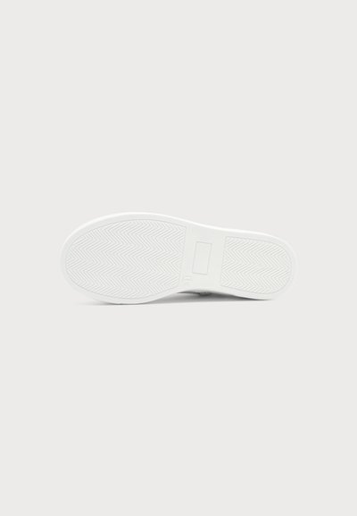 Semelle blanche de basket avec motif en arêtes de poisson et détail rectangulaire, vue par le dessous sur un fond clair.