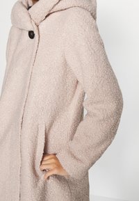 Ljusrosa hooded jacka i texturerat tyg, med knappstängning och sidofickor, med ett mjukt och fluffigt utseende.