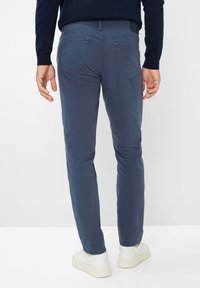 Pantalons slim-fit pour hommes en tissu coton bleu foncé, présentant une texture lisse, un design à cinq poches et un patch logo discret à la taille.