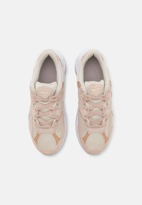 Paire de baskets Nike beige et marron clair avec détails en mesh et daim, vue de dessus sur fond blanc.