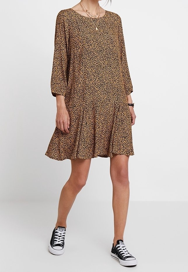 Vestido de estampado de leopardo con mangas tres cuartos, silueta acampanada y escote redondo, combinado con zapatillas negras y collares en capas.