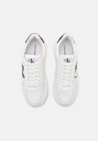 Vita sneakers i slätt läder med svarta detaljer och texturerad sula. Har snörning och Calvin Klein-logotyp på tungan.