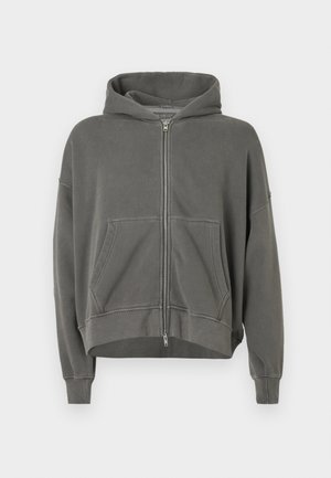 Harmaa vetoketjuhuppari, jossa on hupullinen muotoilu, etutaskut ja lyhennetty malli. Raskaan tuntuiset materiaalit, rento istuvuus ja ribatut hihansuut.