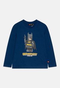 Långärmad t-shirt i marinblå färg i bomull, med en LEGO Batman grafik och en gul "Gotham City"-text nedanför. Mjuk textur med rund hals.
