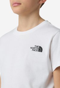 Biała bawełniana koszulka z okrągłym dekoltem. Na lewej piersi czarne nadrukowane logo. Krótkie rękawy, klasyczny krój.