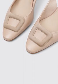 Bailarinas desnudas de cuero con punta afilada, que presentan un acento cuadrado de gamuza beige en el empeine, textura suave y un diseño minimalista.