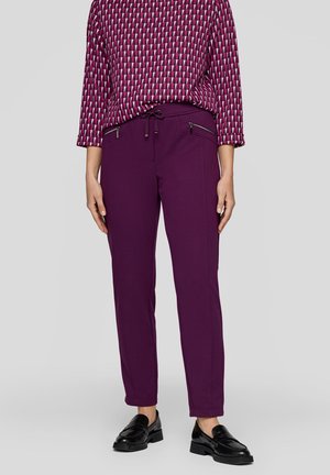 Purple pants with a tapered cut, featuring zippered pockets and elastic drawstring waist. Paired with a geometric patterned top in shades of pink.