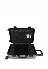 Gray hard-shell suitcase with a retractable handle, four wheels, black interior mesh pocket, and identification label inside.