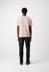 Stribet kortærmet T-shirt med pink og blå striber; parret med sorte bukser. Enkel design med en afslappet pasform.