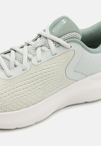 Světle šedá sportovní bota s síťovinovým svrškem, texturovanou tkaninou a gumovou podrážkou. Obsahuje zaoblenou špičku, design na šněrování a decentní značení.